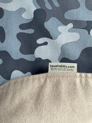 Close up and back side of BAVETTE cotton  adult bib in dark and light blue camouflage design with beige flannel back side and Bavette Bibs label.