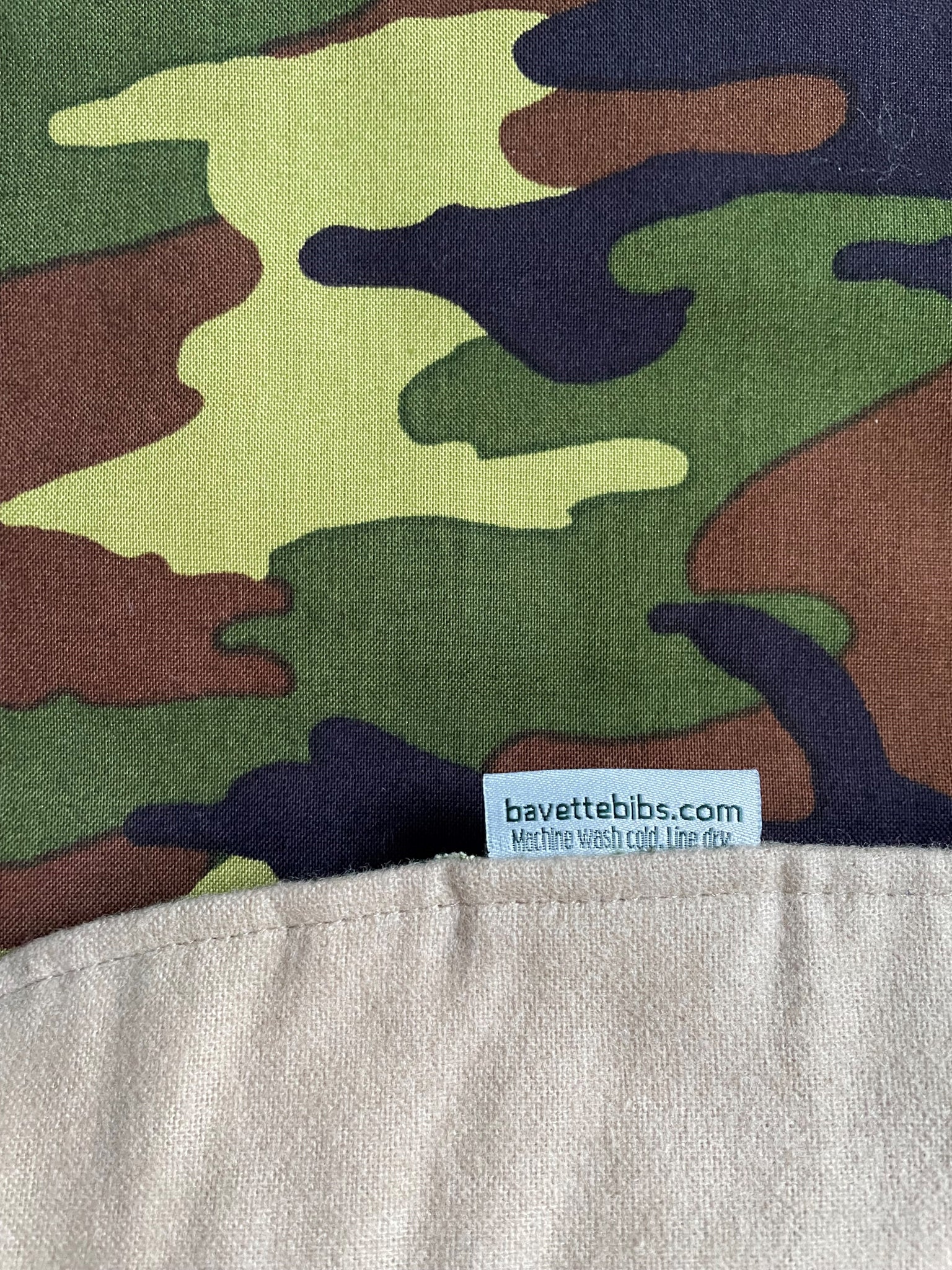 Close up of brown, black, and green camouflage design of BAVETTE adult bib