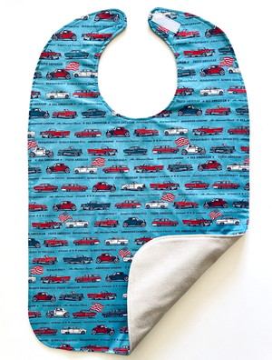 Two sides of BAVETTE adult bib featuring red, white, and blue classic car design and three layers of machine washable premium cotton, Velcro back closure, 26" x 17